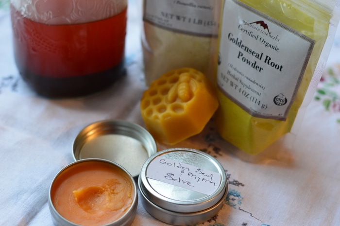 Ingredients for goldenseal, myrrh, and frankincense salve with finished salve in foreground.