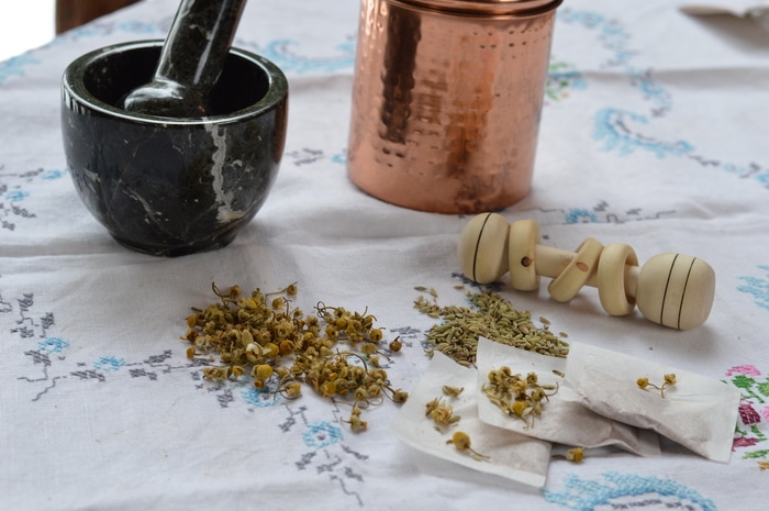 A mortar and pestle, container, baby rattle and homemade tea for colic