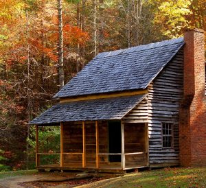 A farmhouse with autumn foliage in the background