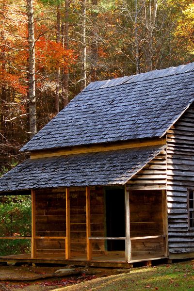 A farmhouse with autumn foliage in the background