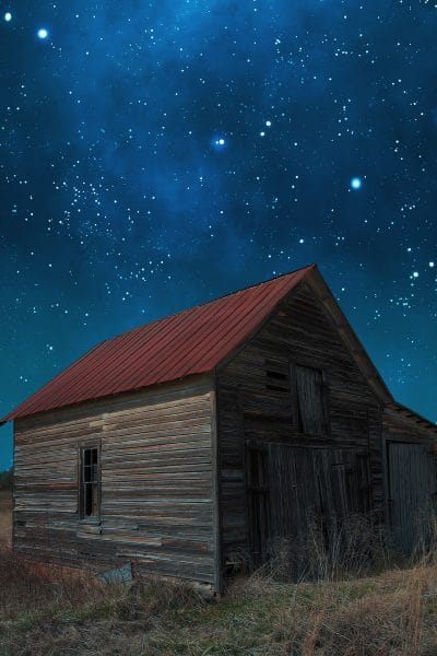 A starry night with an old barn in the foreground