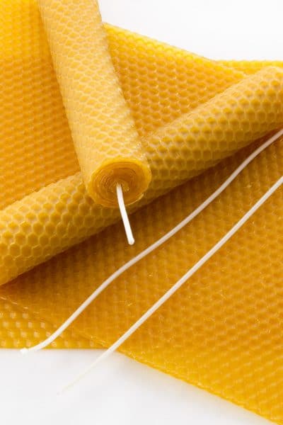 Beeswax candles and wicks laying on a beeswax sheet