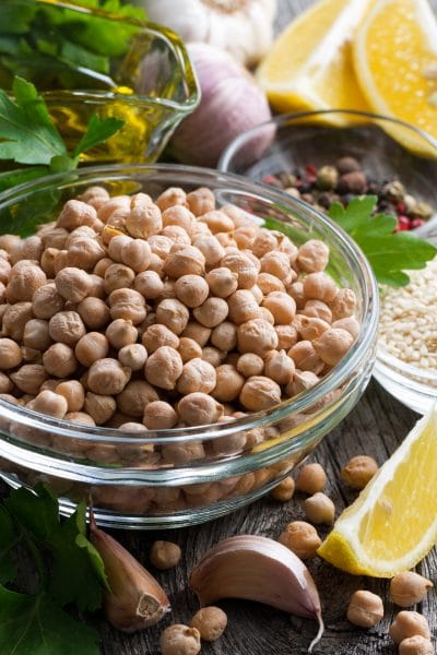 Chick peas, garlic, lemon wedges (hummus ingredients) on a cutting board