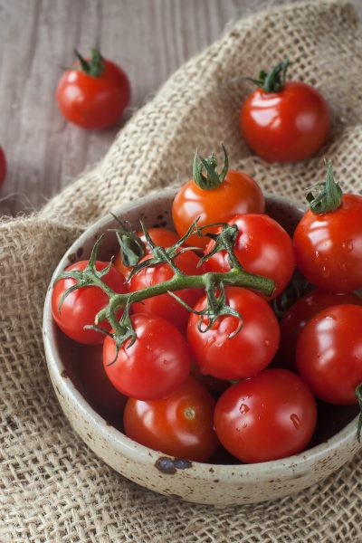 Fresh cherry tomatoes in a bowl on folded burlap