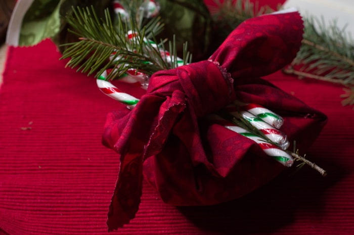 gift wrapped with fabric, a sprig of pine and a candy cane