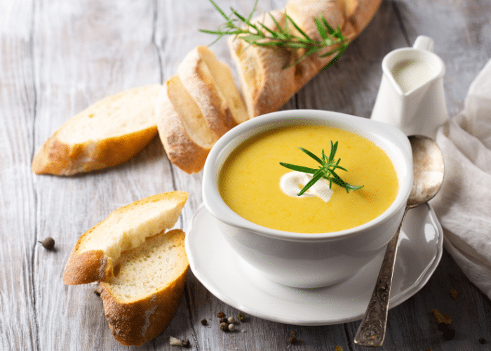 a bowl of cream of cheddar cream soup in a white bowl with a bagette with a sprig of parsley on it, on a grey tabletop background. Make your own dried cream soup base for this type of soup!