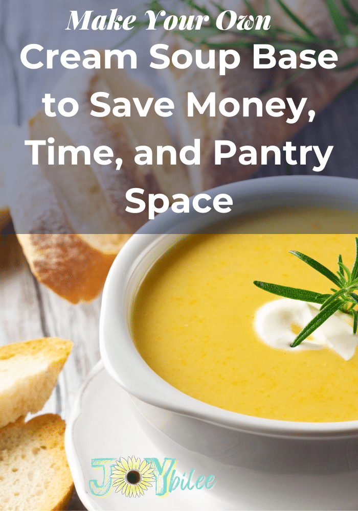 a bright yellow cream soup with a dollop of sour cream and a sprig of rosemary on top, on a grey table background with slices of a baguette.